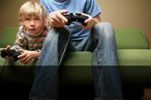 A man and child playing video games on the couch.